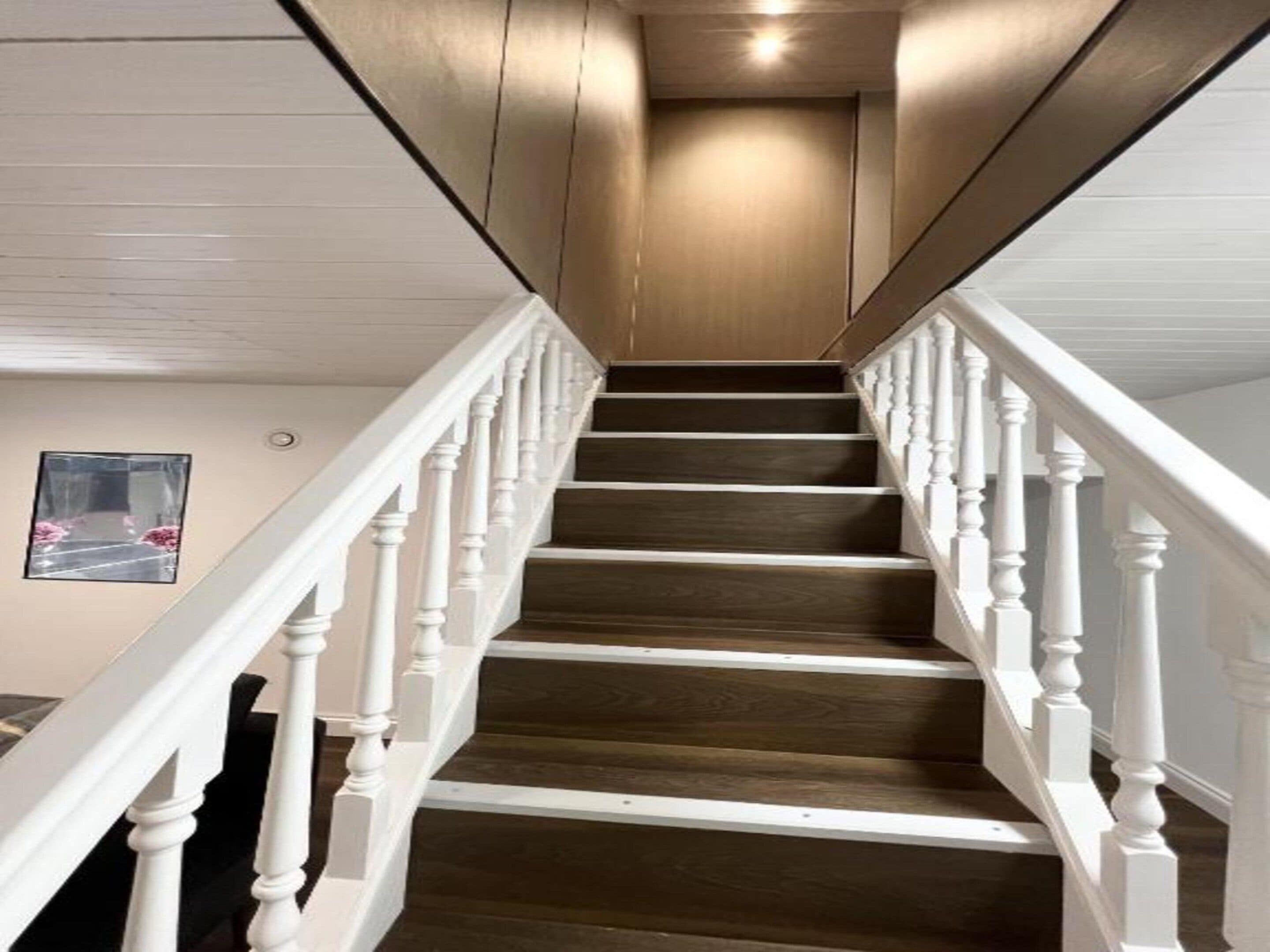 A staircase with white balusters and dark wooden steps leading to a landing.