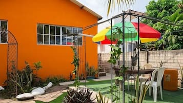 Una propiedad residencial con un césped cuidado, un patio con mobiliario exterior y un paraguas llamativo.