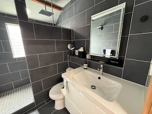 Un baño moderno con un espejo grande, un lavabo y un inodoro.