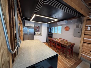 Una cocina compacta con refrigerador, cafetera y una mesa de comedor con sillas.