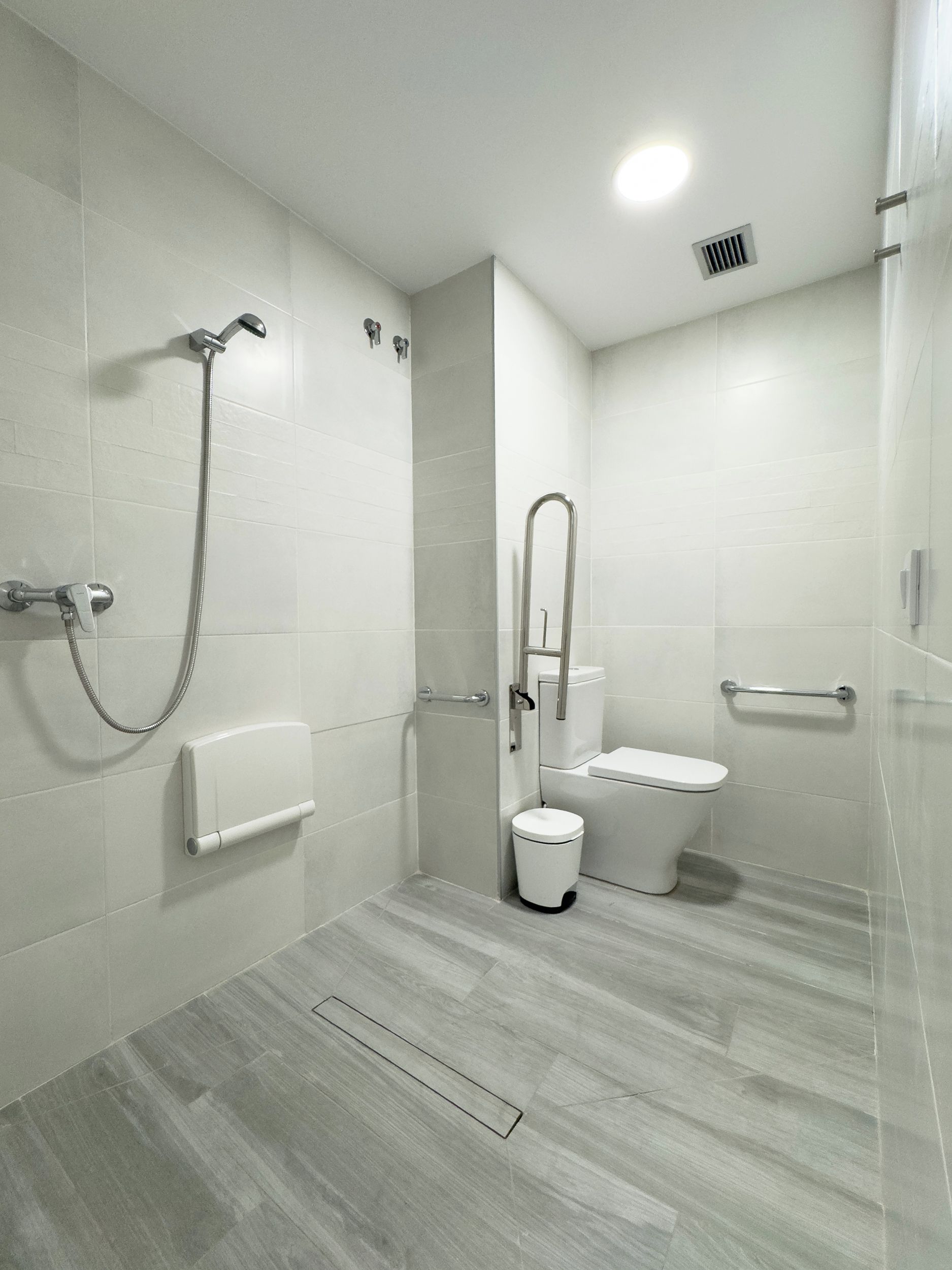 Un baño moderno con ducha, inodoro y secador de manos.