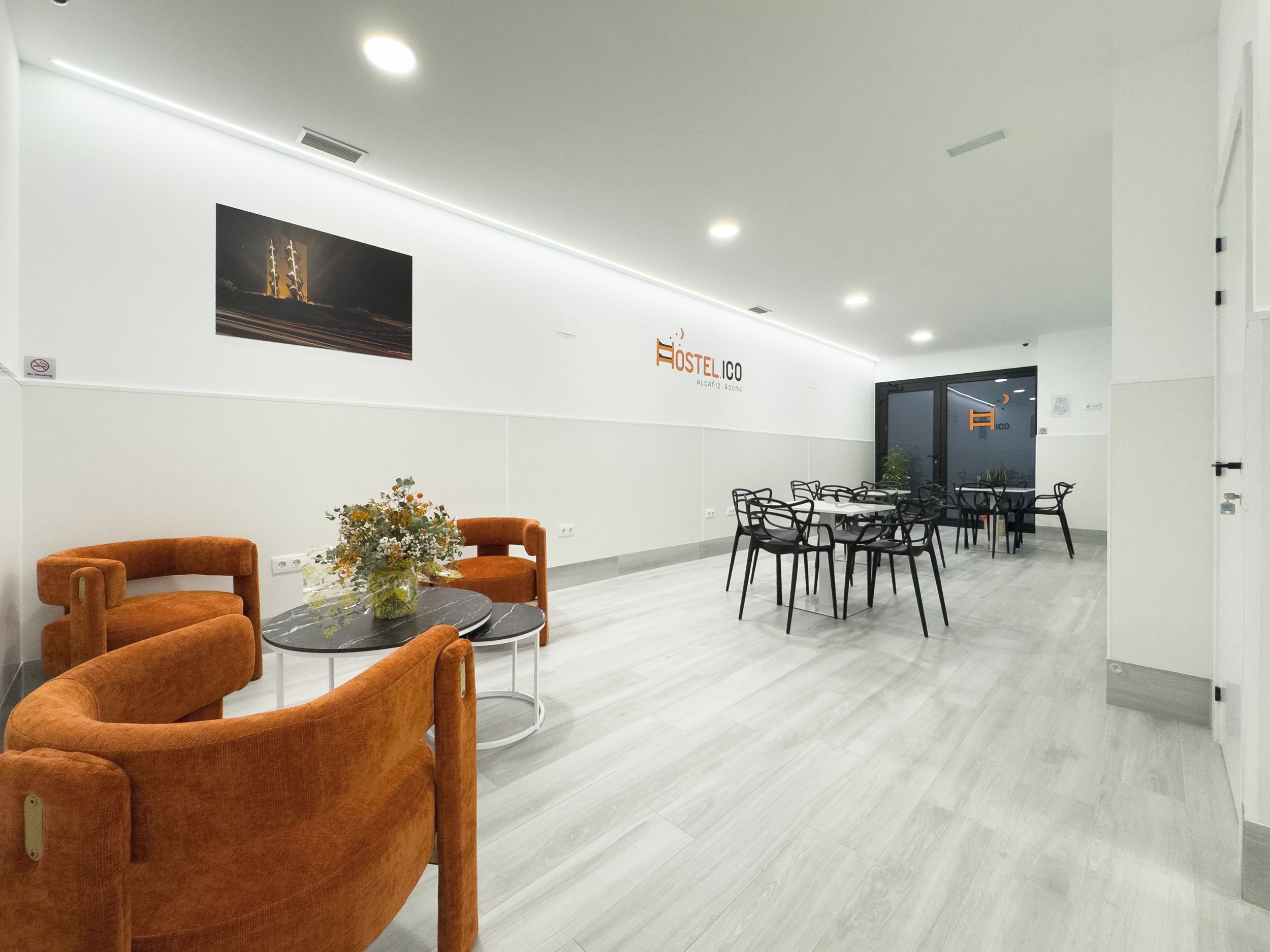 Una camera d'hotel moderna con zona pranzo, divano e tavolo con un vaso di fiori.
