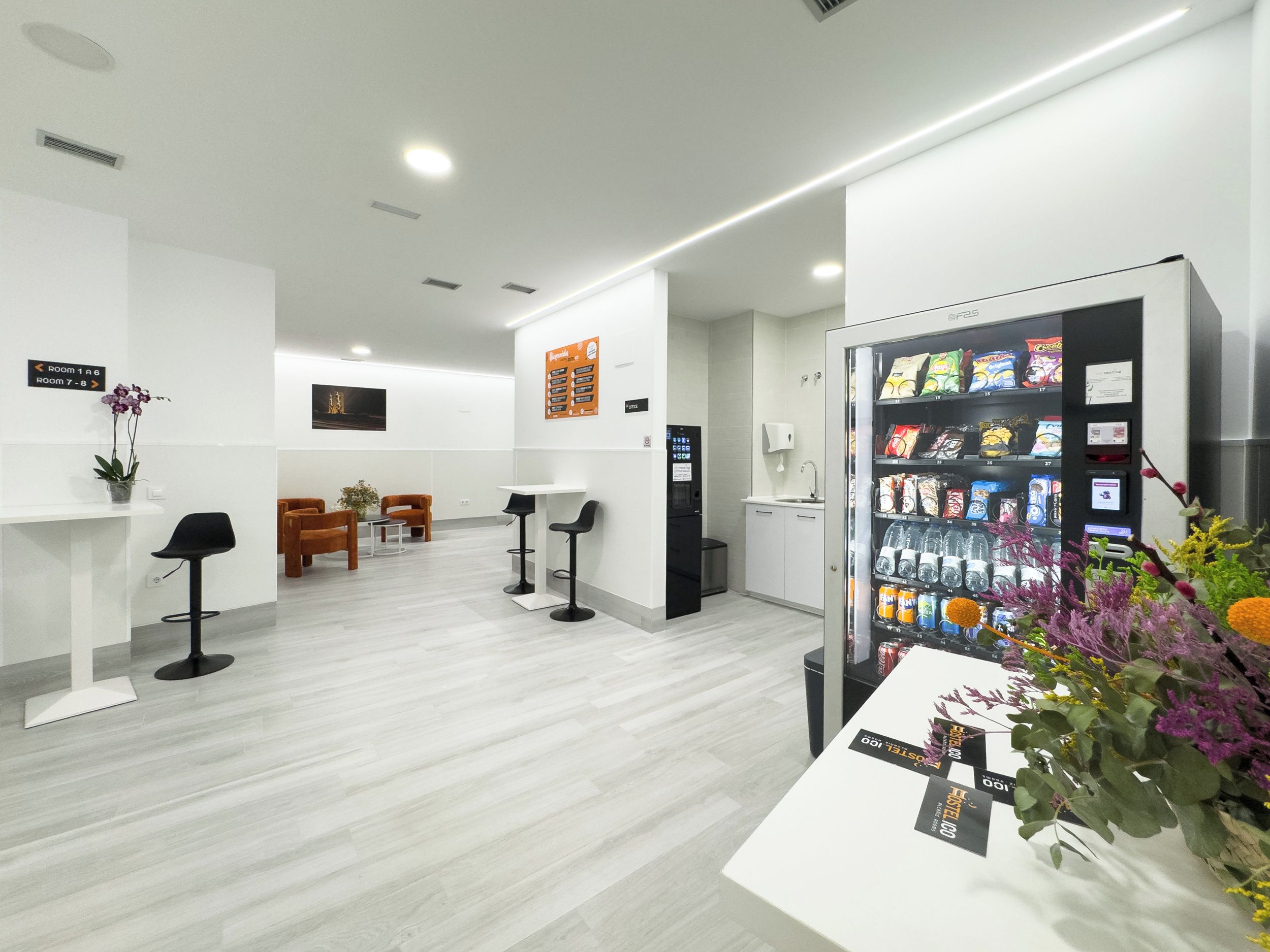 Un espace d’accueil comprenant un comptoir de réception blanc, un coin salon et un distributeur automatique.