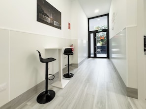A corridor with two black bar stools, a white counter, and a door with a glass panel.