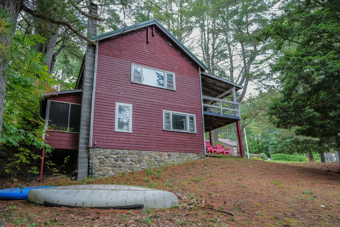 Una casa de dos pisos con base de piedra y fachada roja.