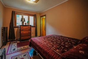 Une chambre à coucher avec un lit, une commode et une fenêtre avec des rideaux.