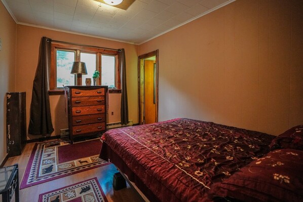 Een slaapkamer met een bed, een kaptafel en een raam met gordijnen.