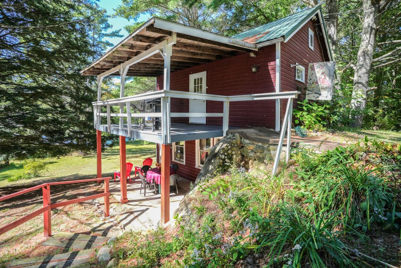 A wooden cabin with a covered porch and a stone staircase leading to a deck.