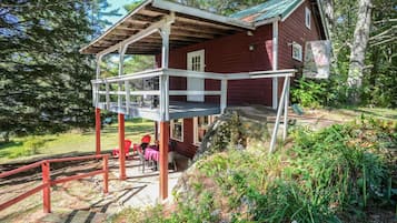 A wooden cabin with a covered porch and a stone staircase leading to a deck.
