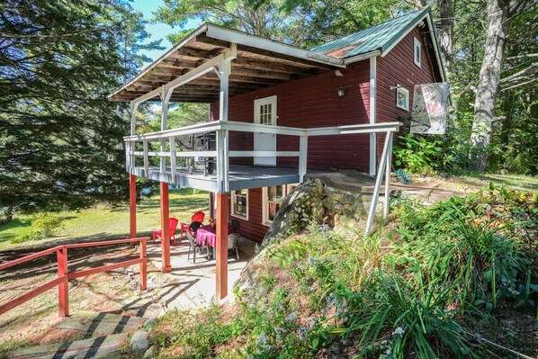 A wooden cabin with a covered porch and a stone staircase leading to a deck.
