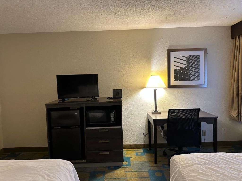 A hotel room with a bed, a desk with a lamp, a television, and a microwave.
