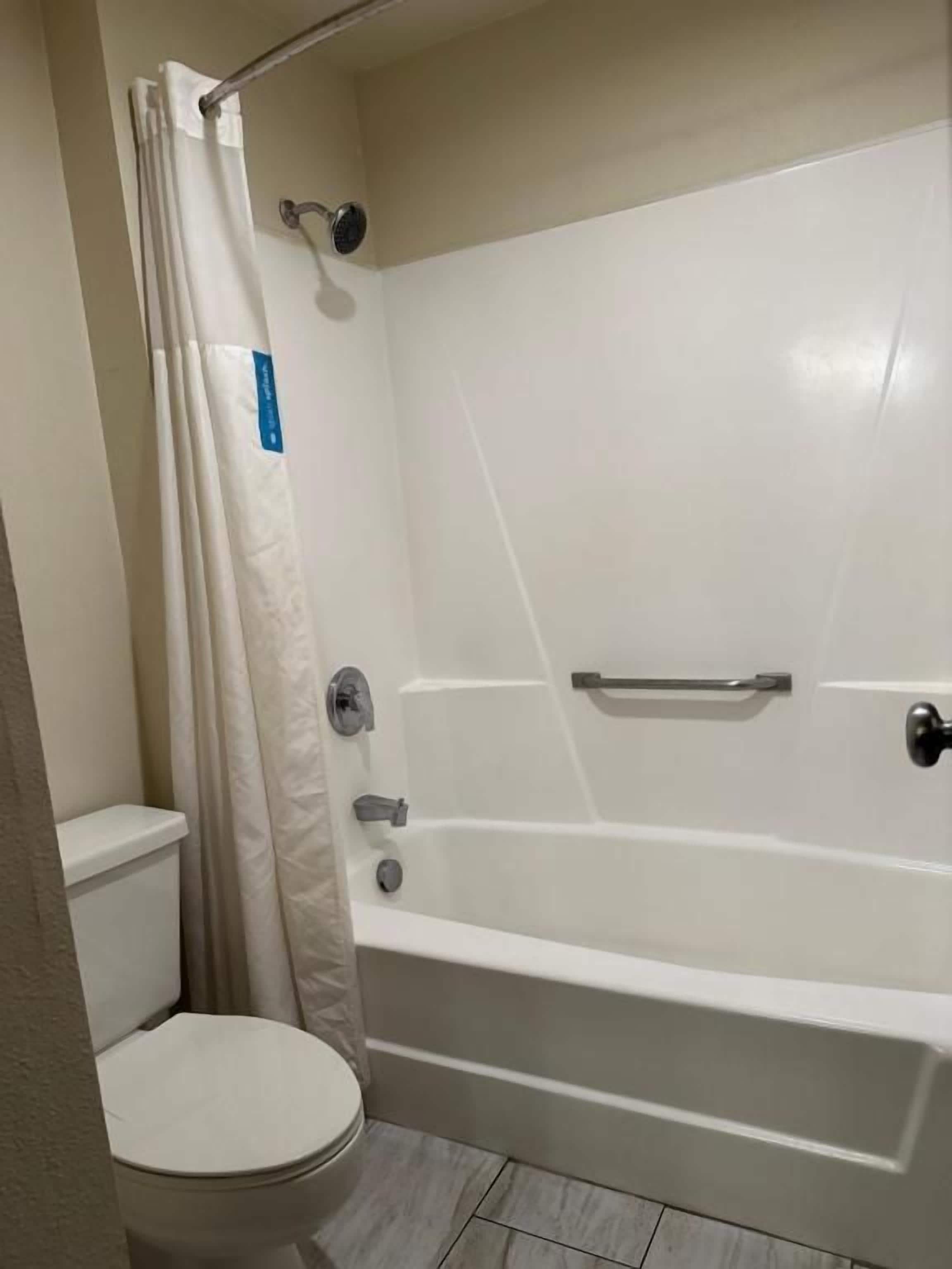 A bathroom with a white bathtub, a toilet, and a shower curtain.