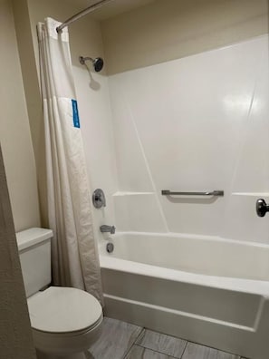 A bathroom with a white bathtub, a toilet, and a shower curtain. - Hotel Inn Milwaukee Mitchell Airport (Milwaukee)