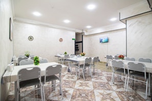 A conference room with tables and chairs, a projector screen, and a tiled floor. - Art hommee (TASHKENT)