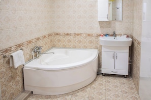 A bathroom with a freestanding bathtub, a sink, and a cabinet. - Art hommee (TASHKENT)