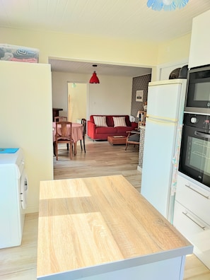 A kitchen with a wooden countertop, a white refrigerator, and an oven. - Apartment 'Studio Cozy à pied de la Plage' with Wi-Fi (Guilvinec)