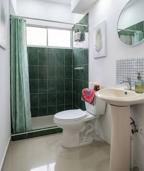 Et badeværelse med toilet, vask og bruser.