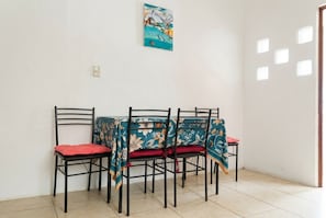 A dining area with four chairs and a table, a painting on the wall, and a door with small windows. - Soothing 2-bedroom house in quaint Playa San Blas getaway near ALL hot spots (Playa San Blas)