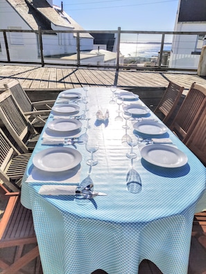 Een eettafel gedekt voor een maaltijd, met stoelen eromheen, met uitzicht op een waterpartij.