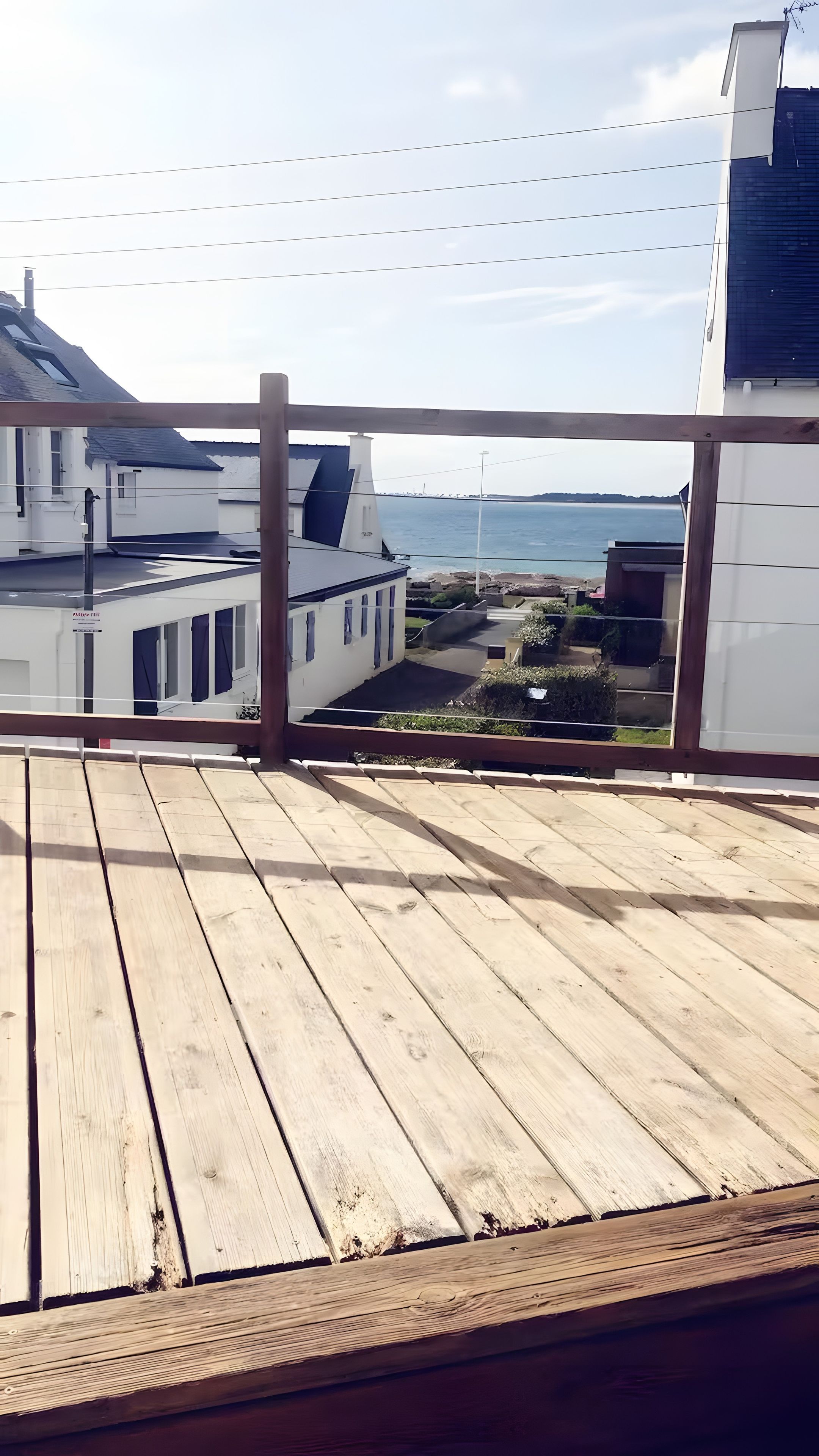 A wooden deck with a view of a coastal area, including buildings and a body of water.