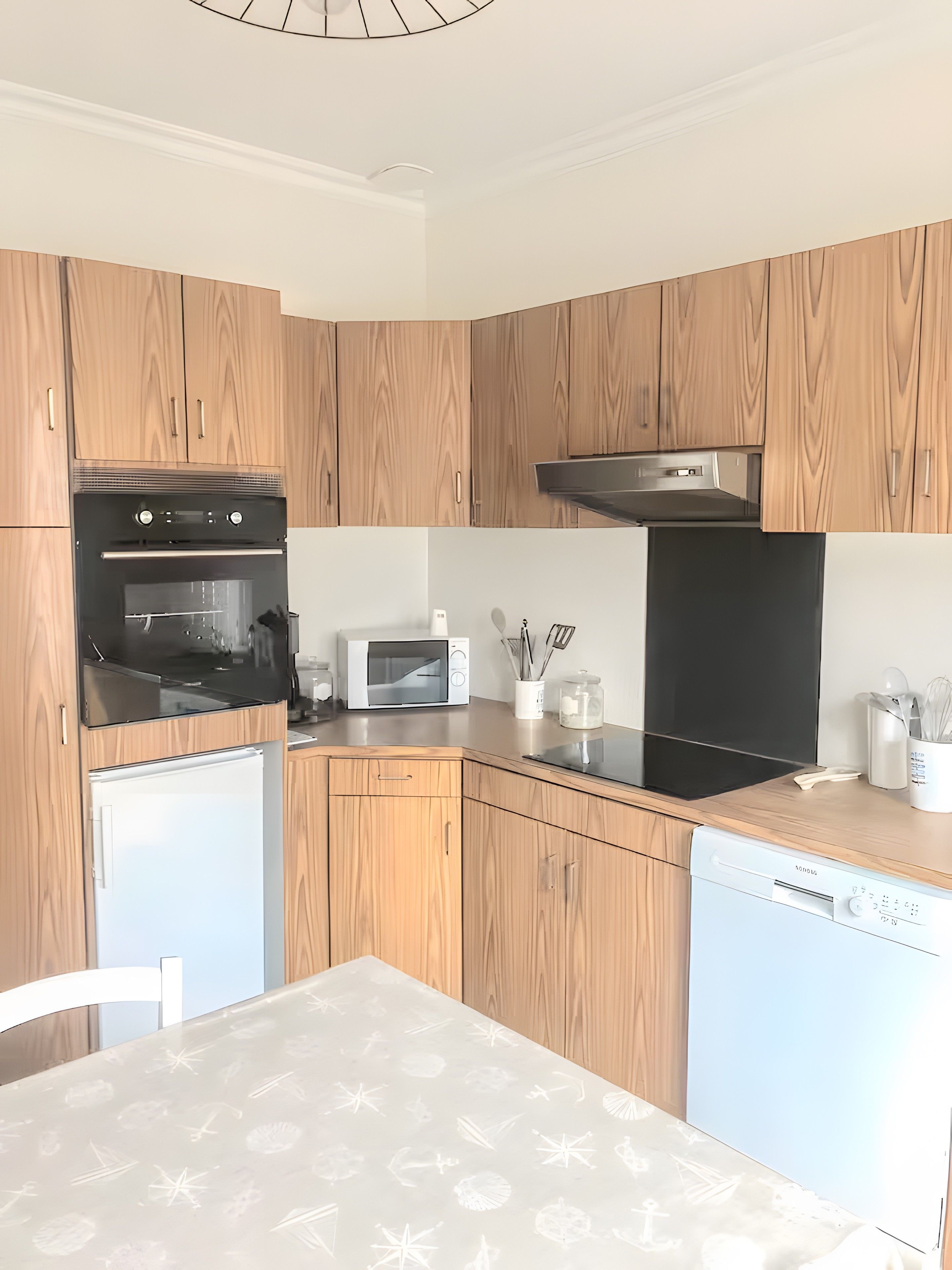 Une cuisine moderne avec des meubles en bois, un four encastré, un micro-ondes et un lave-vaisselle.