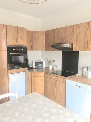 Een moderne keuken met houten kastjes, een inbouwoven, magnetron en vaatwasser.