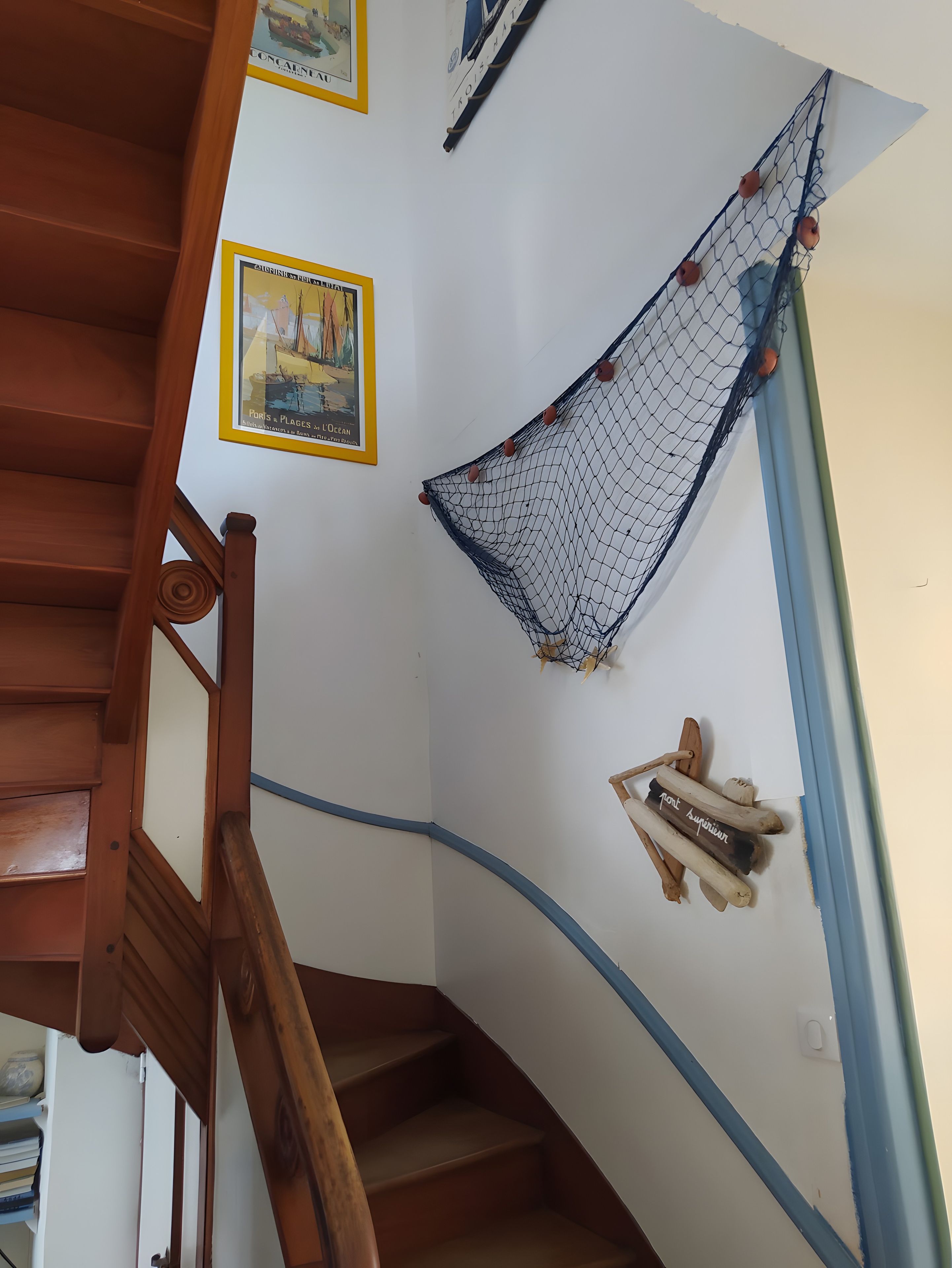 Una scala con ringhiere in legno, un'amaca fissata al muro e un quadro incorniciato.
