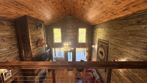 A cabin with a wooden interior, a dining area with a chandelier, and a view of the outside deck.