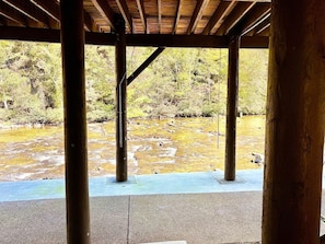 A covered outdoor area with a view of a river and surrounding vegetation.