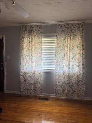 A room with a wooden floor, a window with blinds, and a ceiling fan. - STATEN House
Convenience & Comfort
3 bedroom Family & Pet Friendly (New Albany)
