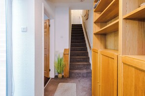 A carpeted staircase with wooden railings and a potted plant at the bottom. - 3-Bed Home, Garden & Driveway, Sleeps 6 (Knutsford)