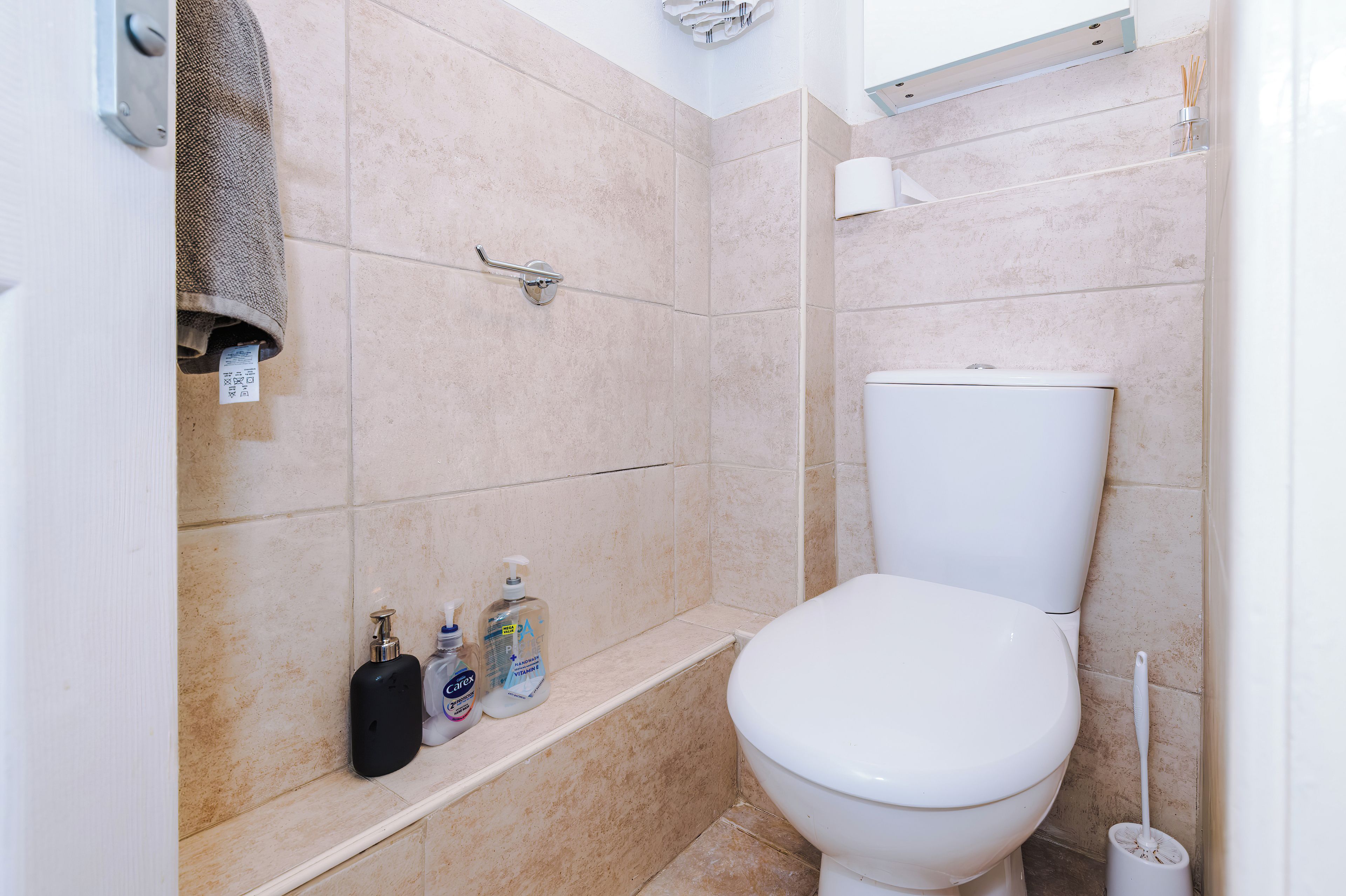 Un baño con inodoro, zona de ducha y estante con artículos de aseo.