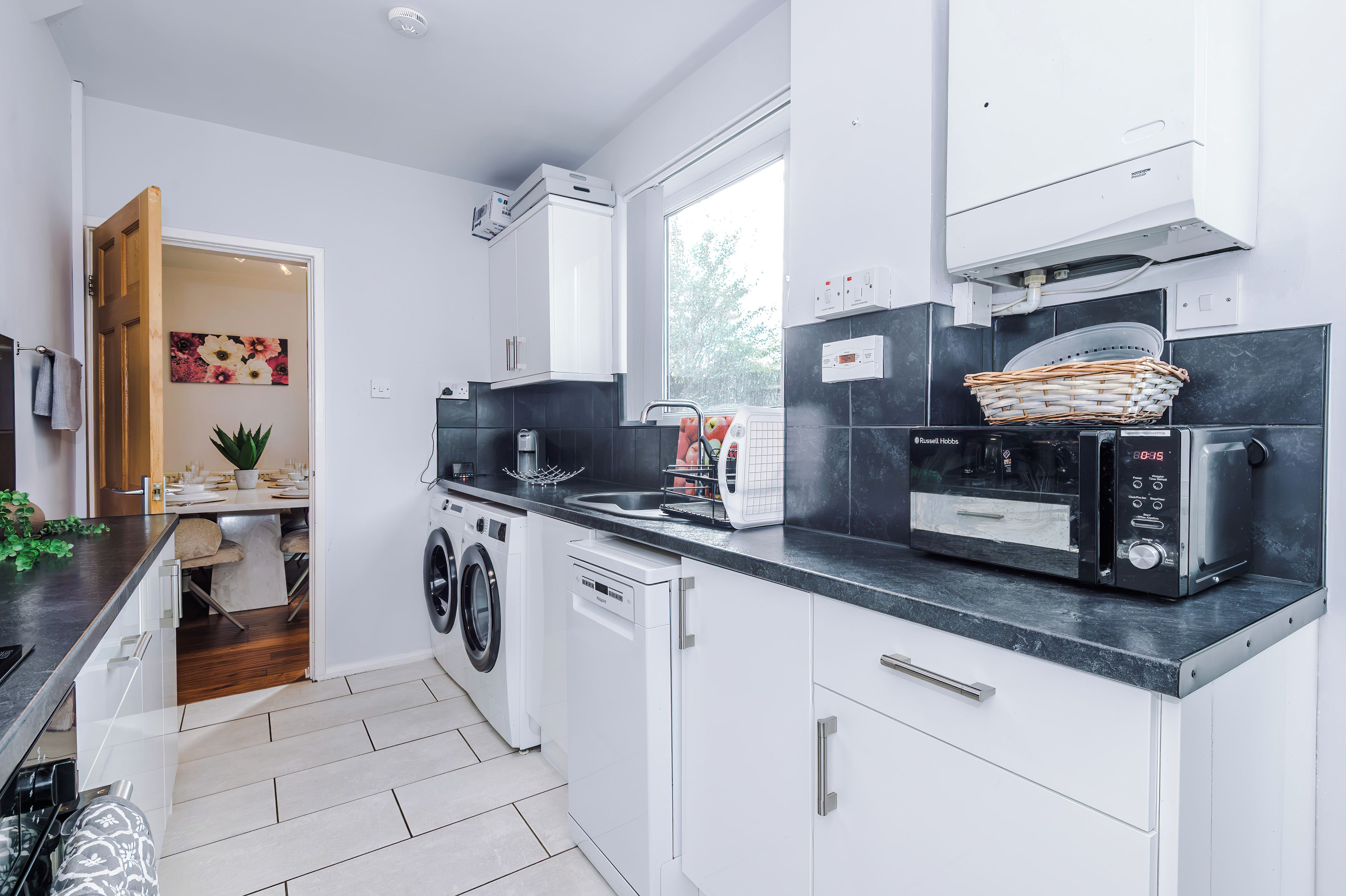 A modern kitchen with built-in appliances, a washing machine, and a dining area with a view.