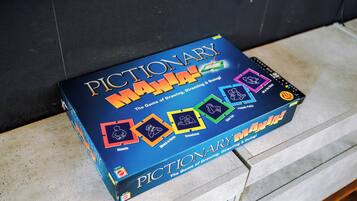 Una caja de juego titulada 'Pictionary Mania!' con diferentes modos de juego y una celebración por su 20 aniversario.
