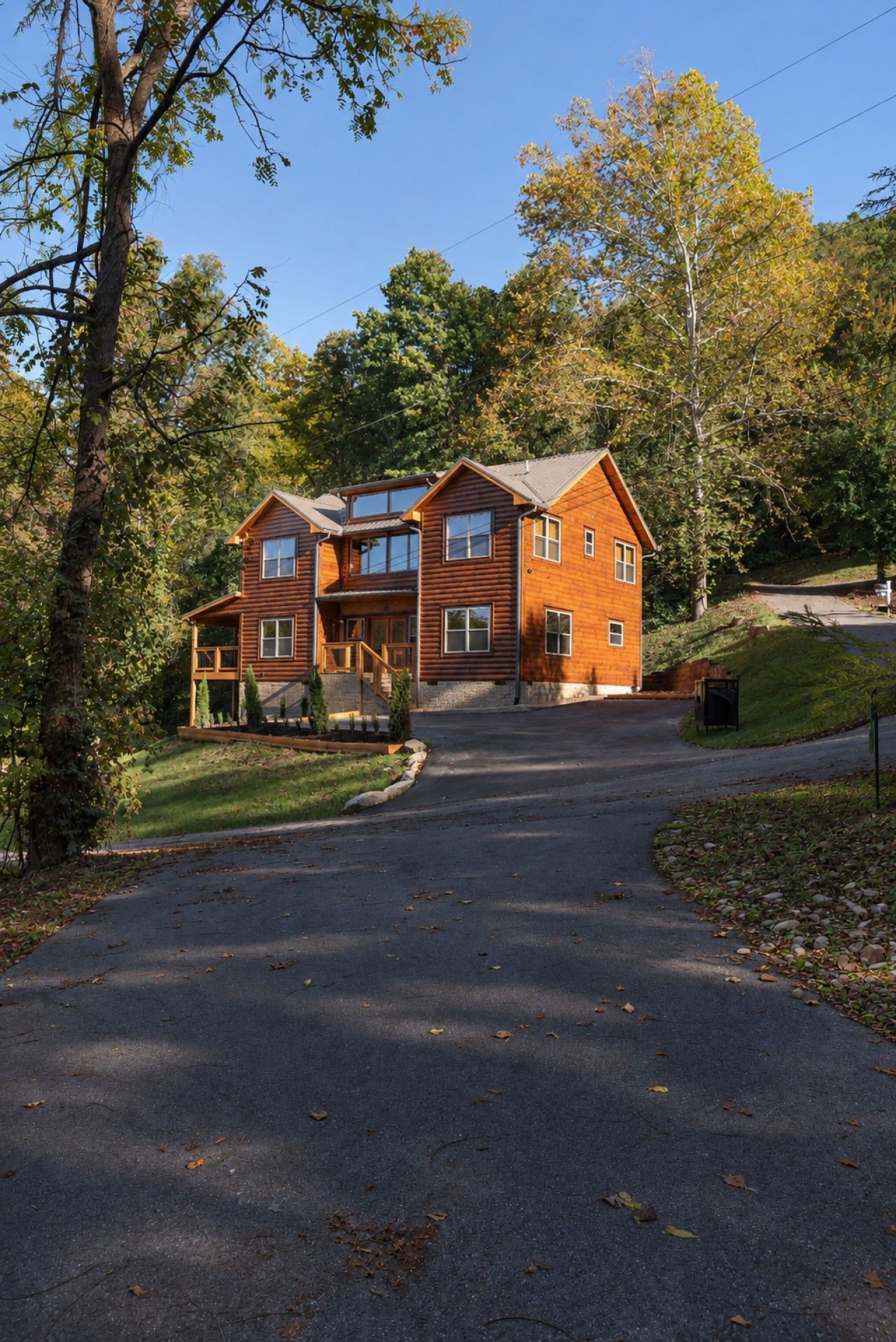 A two-story log cabin with a porch and a driveway leading to the entrance.