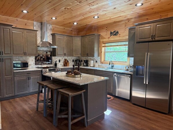 Una cocina con armarios de madera, un refrigerador de acero inoxidable e una isla central con taburetes.