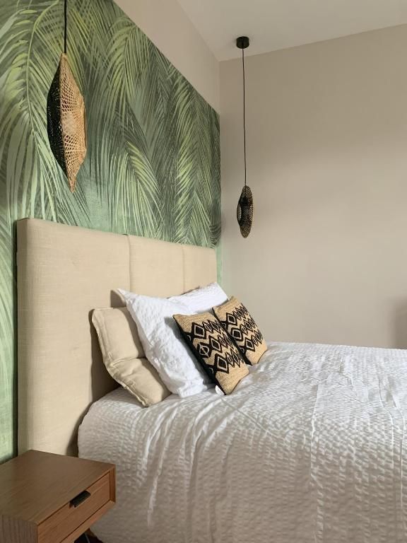A bed with a textured white cover, a beige headboard, and patterned pillows.