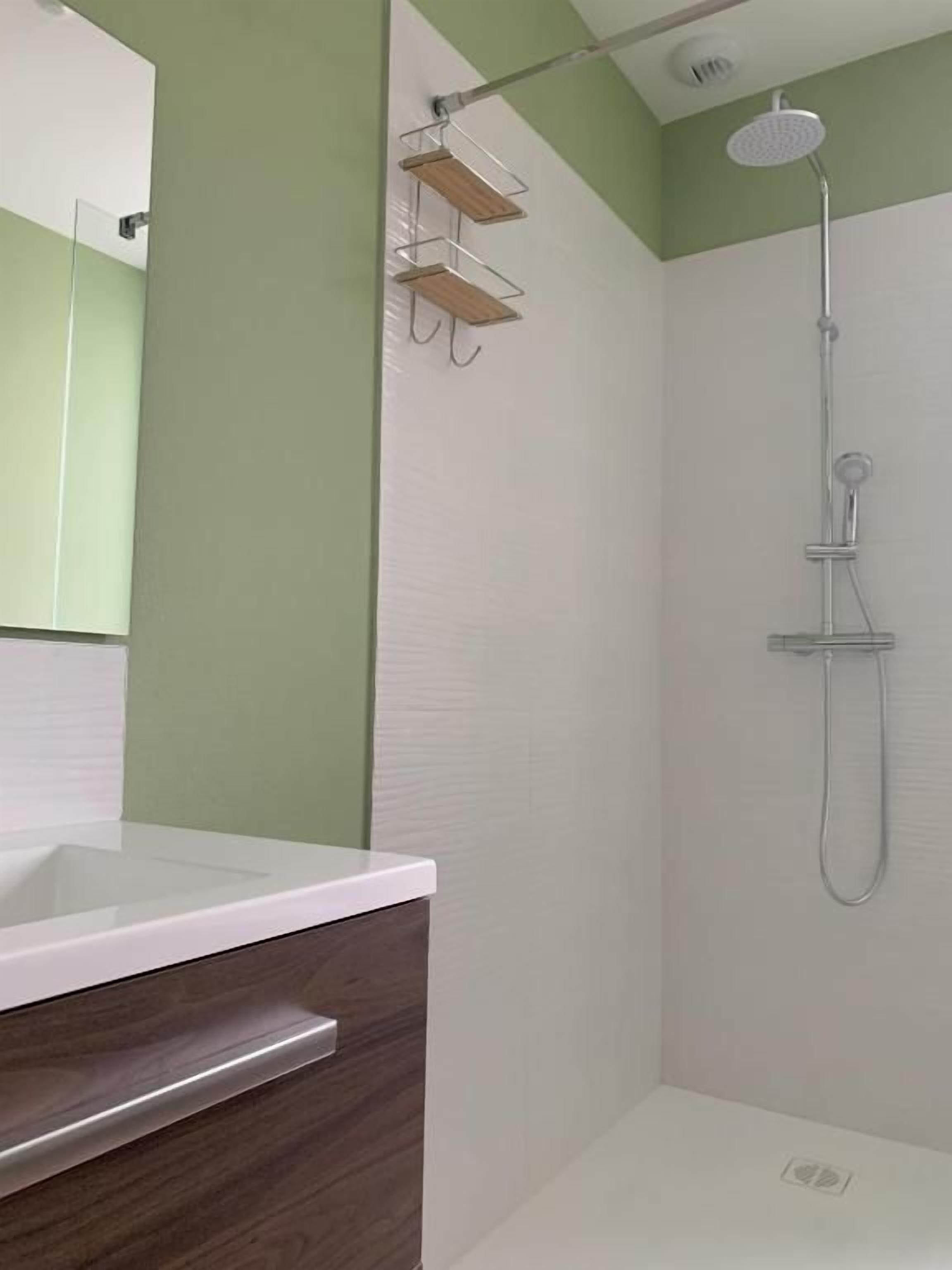 A bathroom with a shower, a sink, and a mirror.