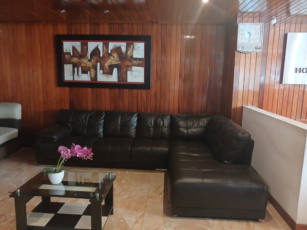 A living room with a leather sofa, a glass coffee table, and a framed abstract painting on the wall.