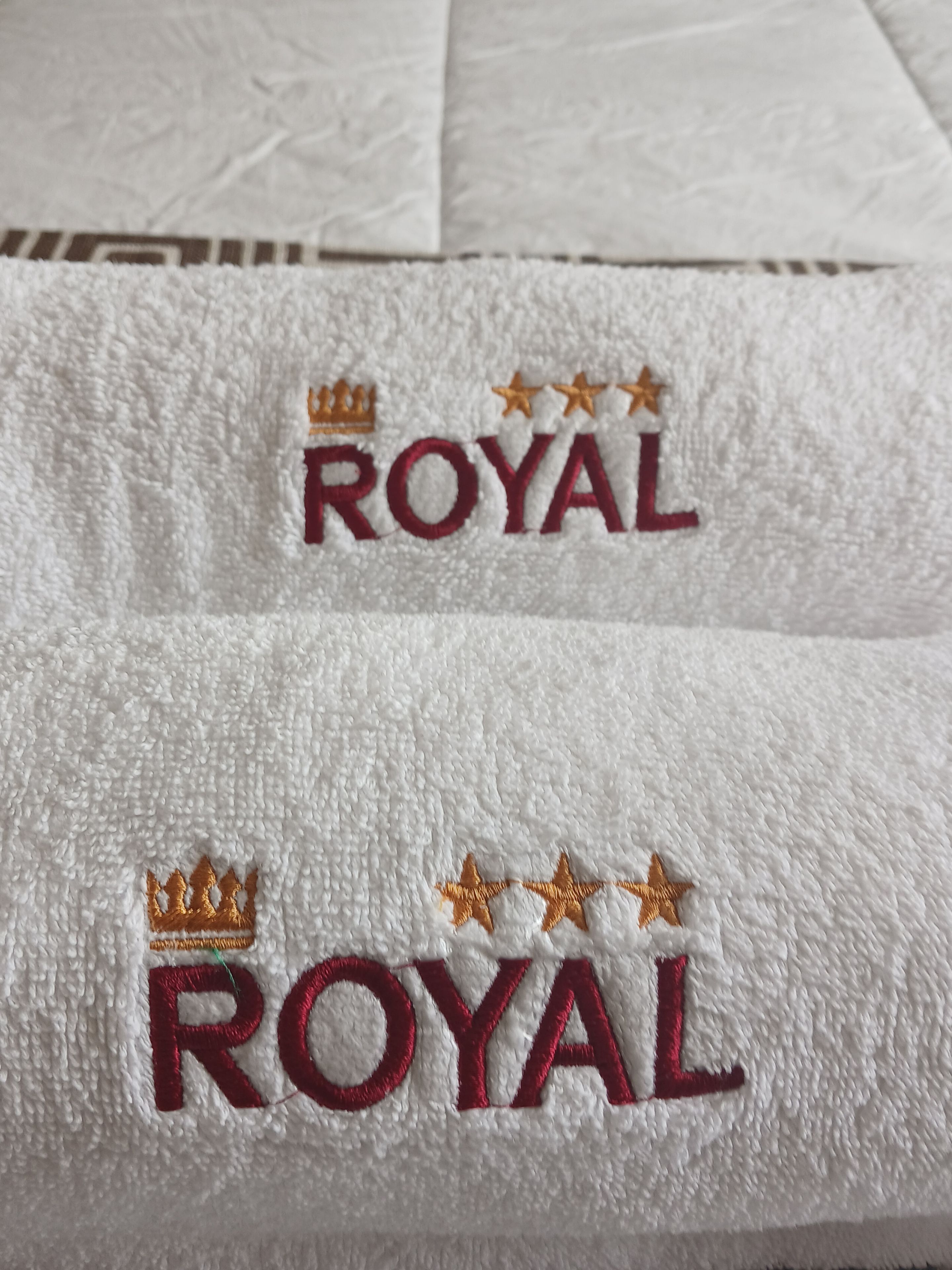 A towel with embroidered text 'ROYAL' and decorative elements.
