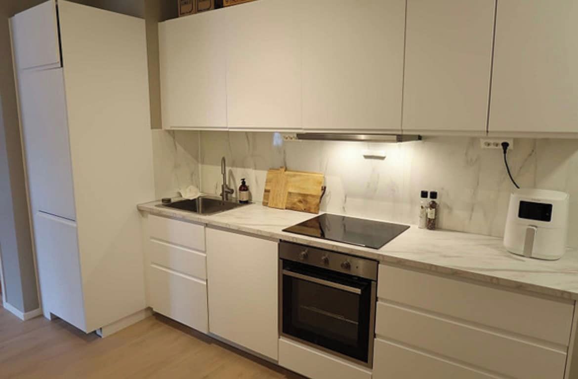 A kitchen with white cabinets, a stove, a sink, and a microwave.