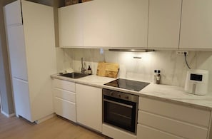 A kitchen with white cabinets, a stove, a sink, and a microwave. - Experience Oslo from the front row (Oslo)