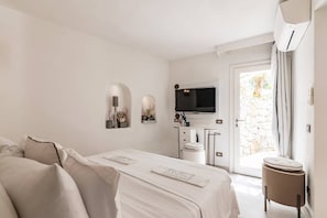 Une chambre d’hôtel comprenant un lit, un bureau, une télévision et une porte donnant sur un balcon.