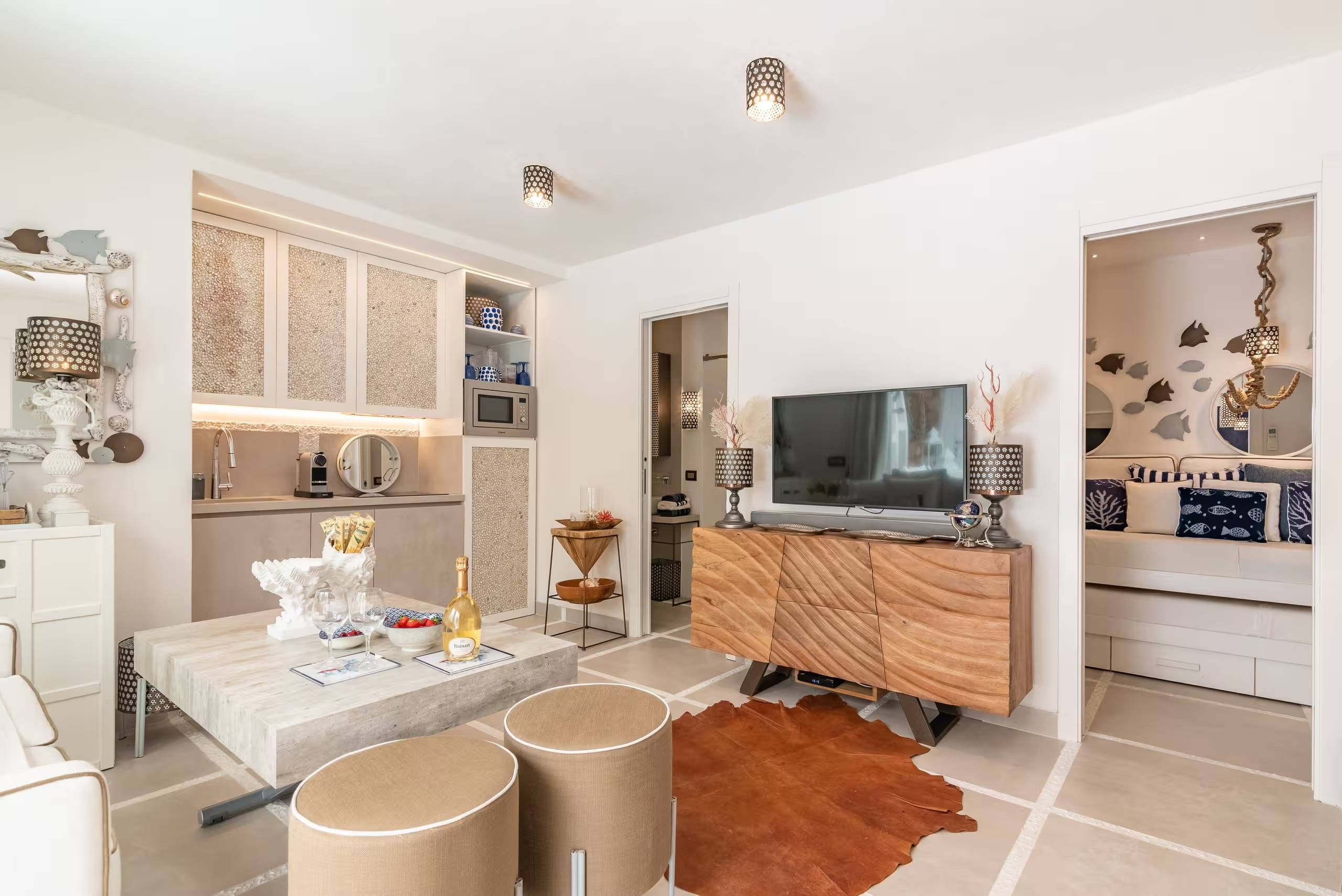 Un soggiorno moderno con TV a schermo piatto, un mobiletto in legno, un'area pranzo con tavolo bianco e un tappeto in pelle marrone.