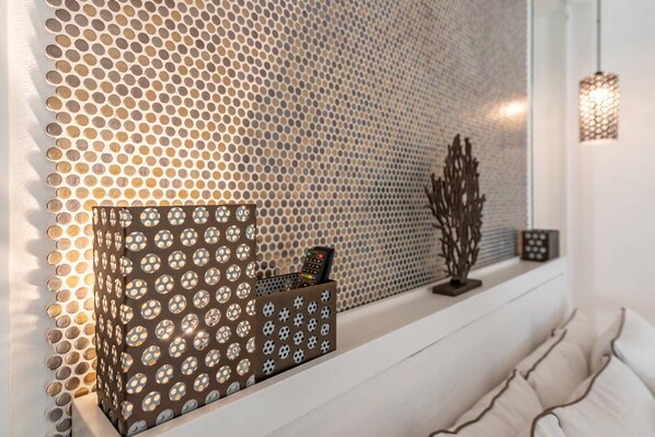 A room with a patterned wall, a shelf with a decorative item, and a hanging light fixture.