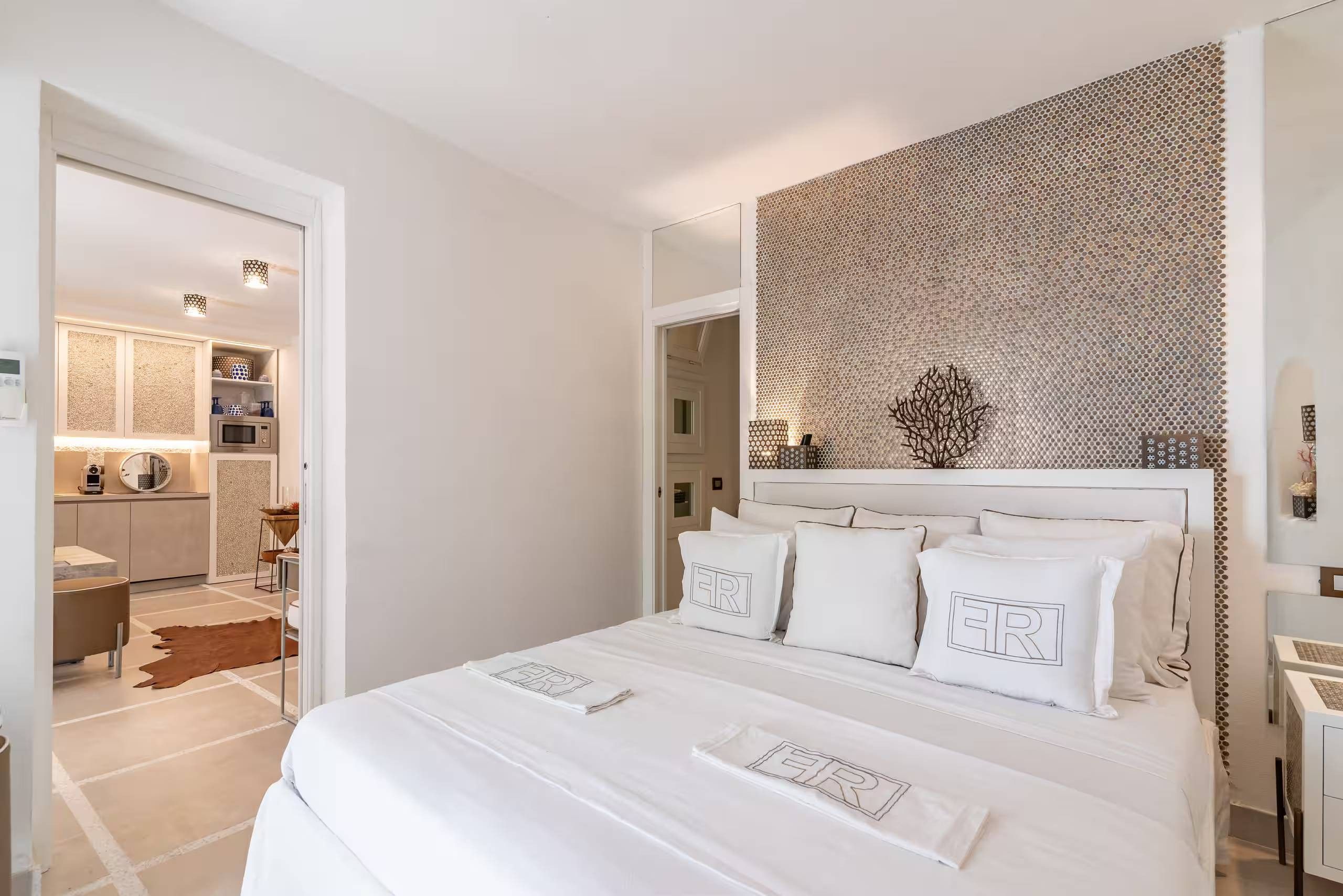 Una camera da letto moderna con un letto grande, una parete decorativa e vista sull'area cucina.