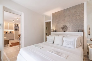 Una camera da letto moderna con un letto grande, una parete decorativa e vista sull'area cucina.