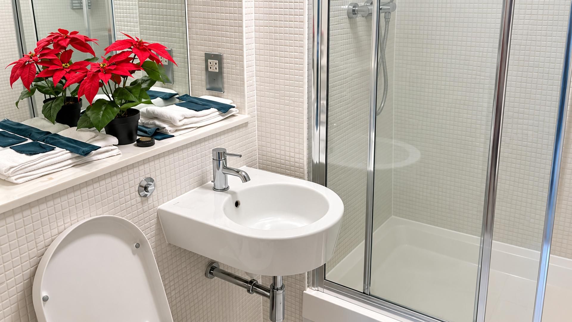 A bathroom with a white sink, a glass shower enclosure, and a toilet.