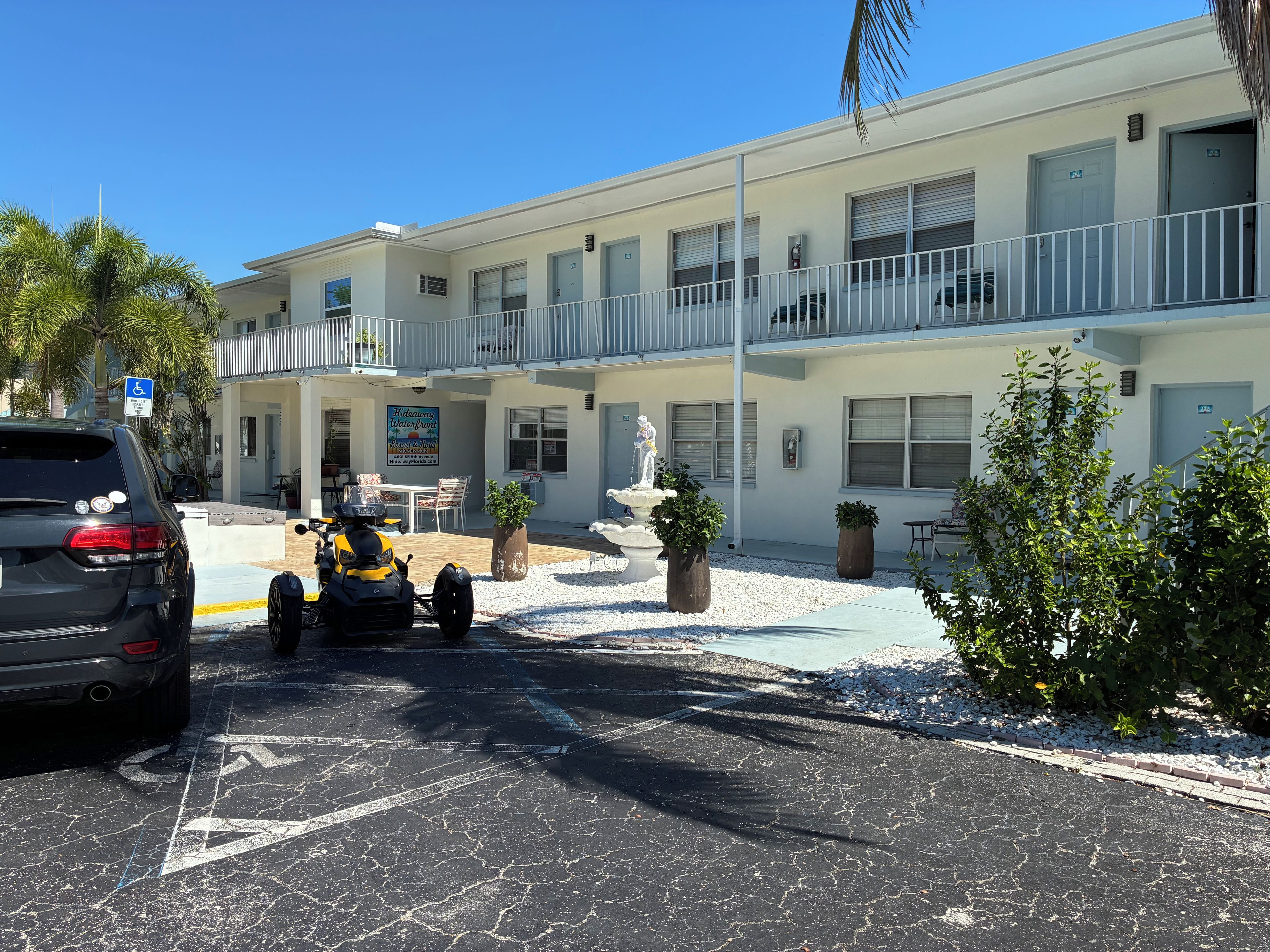 A two-story building with a parking area, a water fountain, and a sign for a waterpark.