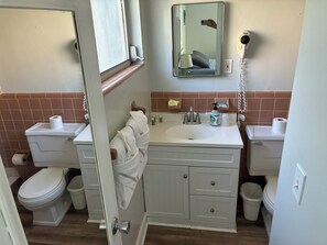 A bathroom with a toilet, sink, mirror, and a towel rack. - Hideaway Waterfront Resort & Hotel (Cape Coral)